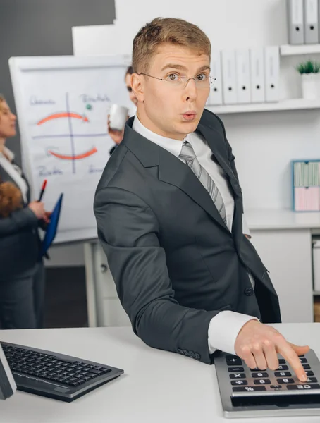 Handsome businessman calculating at calculator — Stock Photo, Image