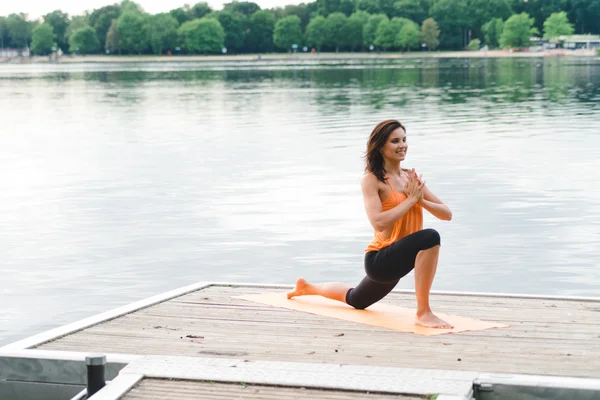 Giovane donna che fa yoga sul lago — Foto Stock