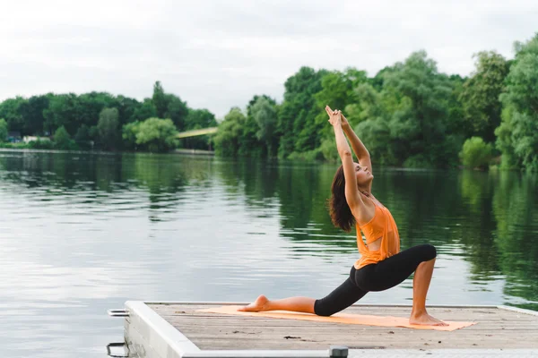 Giovane donna che fa yoga sul lago — Foto Stock