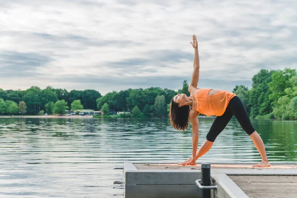Giovane donna che fa yoga sul lago — Foto Stock