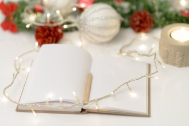 Bir kalem, mum ve yılbaşı dekorasyonu ile boş not defteri 