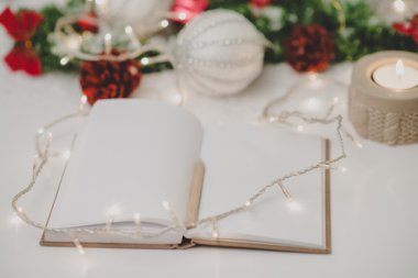 Bir kalem, mum ve yılbaşı dekorasyonu ile boş not defteri 
