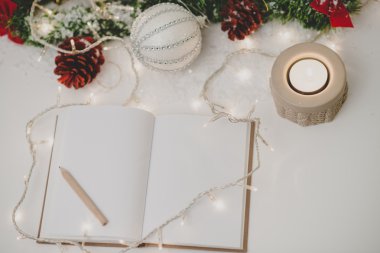 Bir kalem, mum ve yılbaşı dekorasyonu ile boş not defteri 