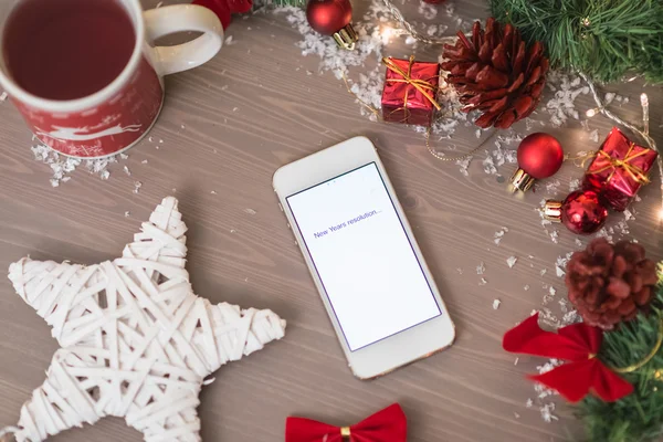 Telefono cellulare scritto anno nuovo risoluzione su con decoratio di Natale — Foto Stock