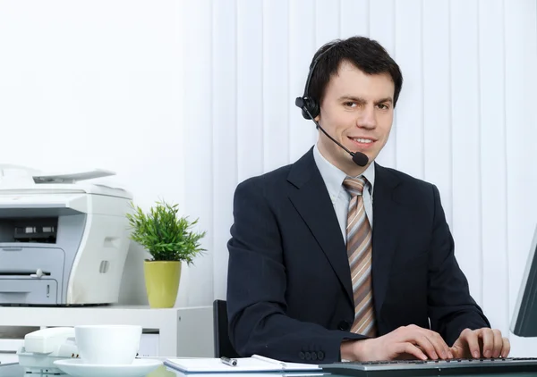 Homem de negócios no escritório fala sobre fone de ouvido — Fotografia de Stock