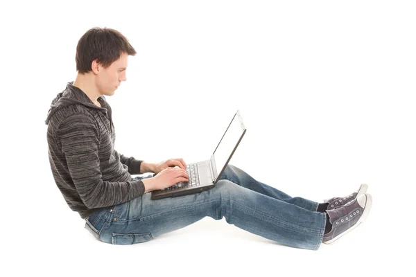 Junger schöner Mann sitzt am Laptop auf dem Fußboden — Stockfoto