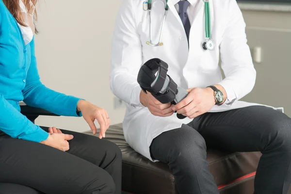 Ortopedista mostra cinta de perna para paciente do sexo feminino — Fotografia de Stock