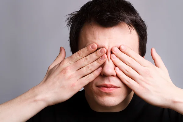 Young man closes his eyes with his hands — Stock Photo, Image