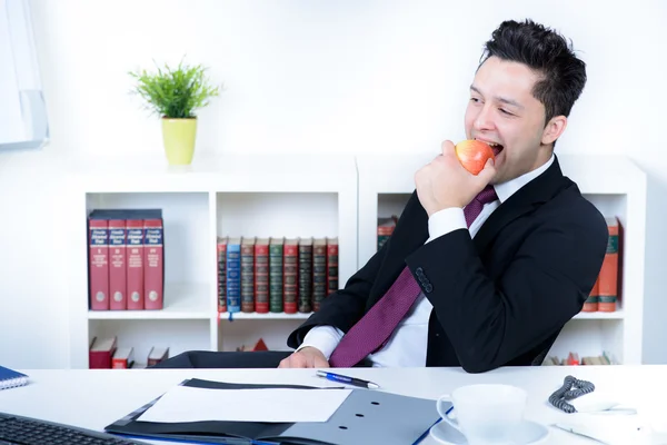 Attraktiver Geschäftsmann im Büro isst einen Apfel — Stockfoto