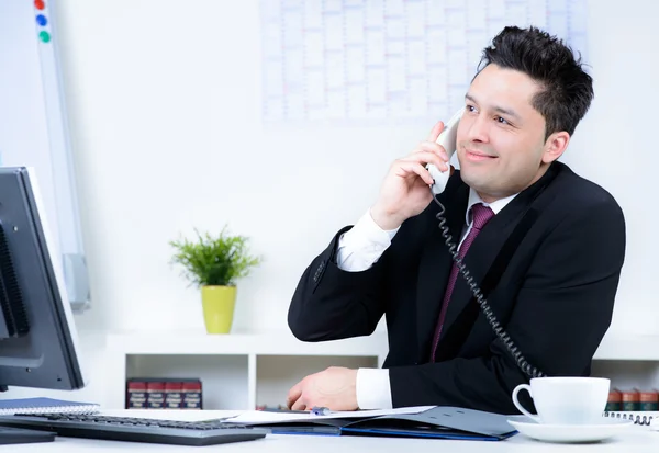 Привлекательный деловой человек в офисе выступает по телефону — стоковое фото