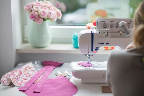 Vista de la sala de costura con máquina de coser, tela, flores y wom — Foto de Stock