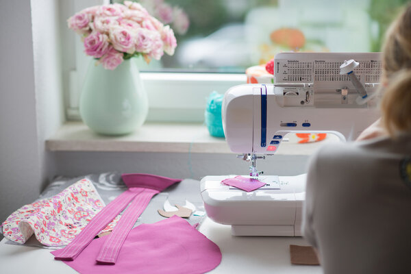 вид швейной комнаты с швейной машинкой, тканями, цветами и тканями
