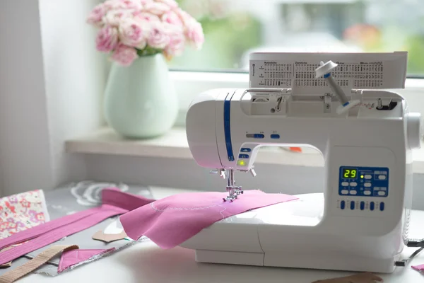 Vista de la sala de costura con máquina de coser, tela, flores y wom —  Fotos de Stock