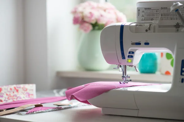 View of sewing room with sewing machine, fabric, flowers and wom — Stock Photo, Image