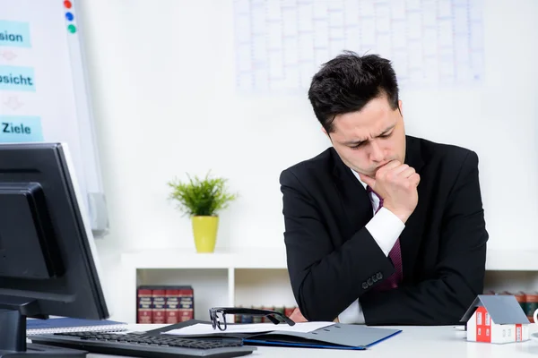 Businessman with a house model in the office — Stock Photo, Image