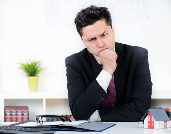 Businessman with a house model in the office. — Stock Photo, Image