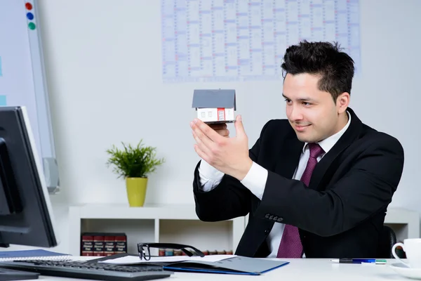 Homme d'affaires heureux avec un modèle de maison dans le bureau — Photo