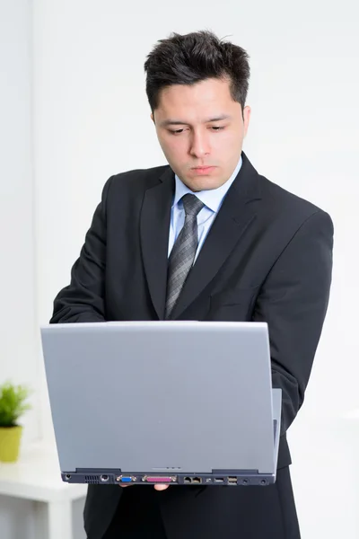 Jeune homme d'affaires travaillant à l'ordinateur portable debout — Photo