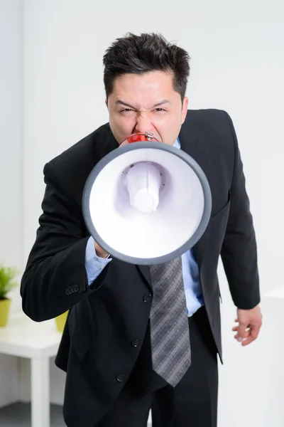 Hombre de negocios enojado en una oficina, gritando en un megáfono — Foto de Stock