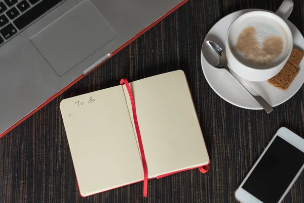 Notizbuch mit Plänen, Morgenkaffee mit Milchschaum, Smartphone und — Stockfoto