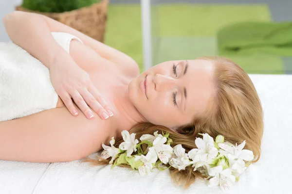 Beautiful woman wrapped in a towel laying in spa with white flow — Stock Photo, Image