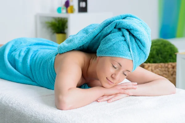 beautiful woman wrapped in blue towel in massage salon