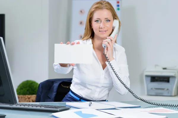 Attraktive vrouw in kantoor op telefoon toont blanco banner — Stockfoto