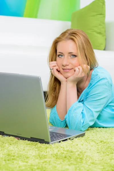 Schöne Frau zu Hause auf dem Boden liegend mit Laptop — Stockfoto