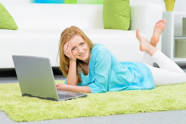 Schöne Frau zu Hause auf dem Boden liegend mit Laptop — Stockfoto