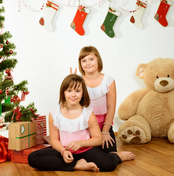 Two cheerful girls have a fun near Christmas tree — Stock Photo, Image