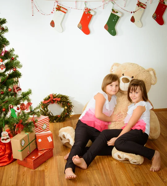 Дві дівчини перед різдвяною ялинкою з подарунками — стокове фото