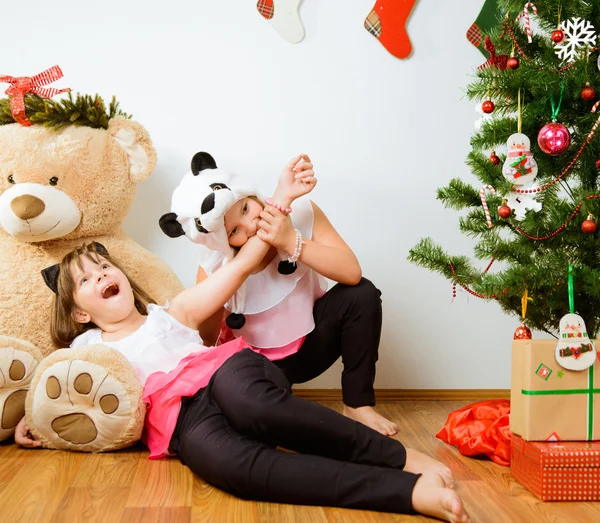 Δύο χαρούμενα τα κορίτσια έχουν ένα διασκεδαστικό κοντά χριστουγεννιάτικο δέντρο — Φωτογραφία Αρχείου