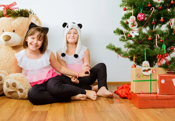 Δύο χαρούμενα τα κορίτσια έχουν ένα διασκεδαστικό κοντά χριστουγεννιάτικο δέντρο — Φωτογραφία Αρχείου