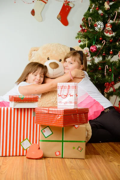 Δύο κορίτσια μπροστά από το χριστουγεννιάτικο δέντρο με τα δώρα — Φωτογραφία Αρχείου