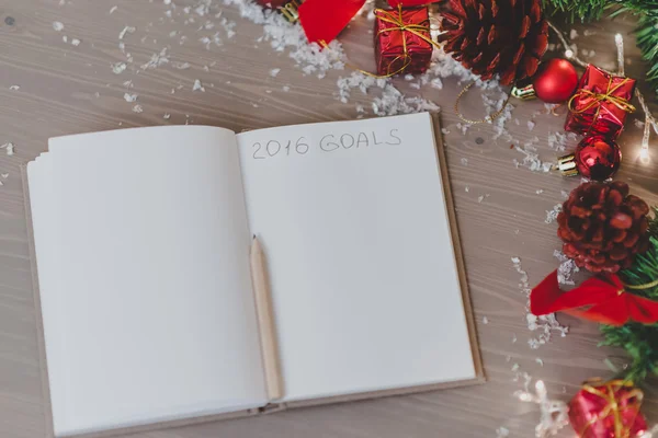 Notepad with a pensil and xmas decoration written 2016 goals — Stock Photo, Image
