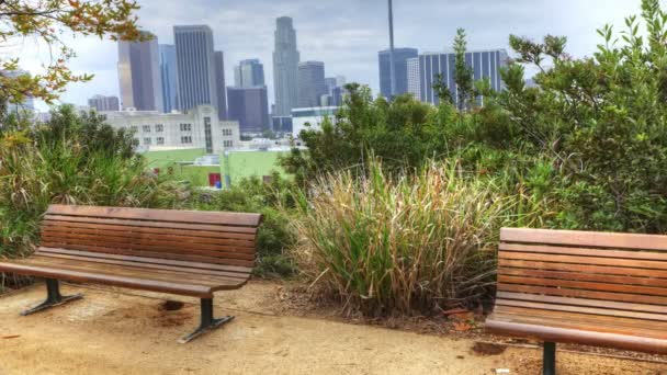 Vue de Los Angeles skyline avec banc de parc au premier plan — Video