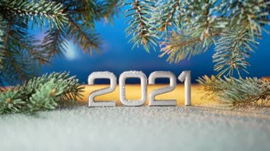 Kapatın. Yeni yıl rakamları 2021. Kar yağıyormuş. Kar yağıyor. Bir Noel ağacının dallarında ya da mavi bir arka planda çam ağacında. Makro gümüş yazıtlar. Tarih yansıtılıyor. metin için boşluk kopyala. 