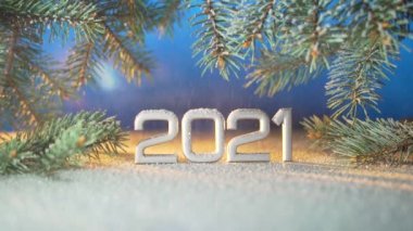 Kapatın. Yeni yıl rakamları 2021. Kar yağıyormuş. Kar yağıyor. Bir Noel ağacının dallarında ya da mavi bir arka planda çam ağacında. Makro gümüş yazıtlar. Tarih yansıtılıyor. metin için boşluk kopyala. 