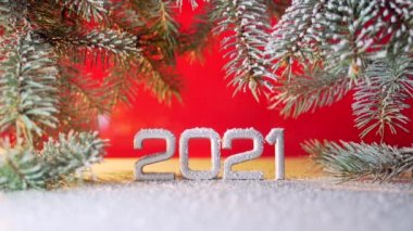 Kapatın. Yeni yıl rakamları 2021. Kar yağıyormuş. Kar yağıyor. Noel ağacının dallarında ya da kırmızı arka planda çam ağacında. Makro gümüş yazıtlar. Tarih yansıtılıyor. metin için boşluk kopyala. 