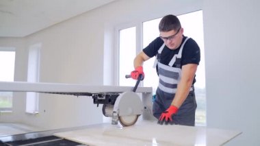 Tiler ıslak testere makinesinde fayans kesiyor. Usta fayansları keser. Sıvı için küvetli daire testere. Döşeme Üretim Atölyesi. Kişi taş ve büyük seramik fayanslarda çalışıyor. Profesyonel ekipman 