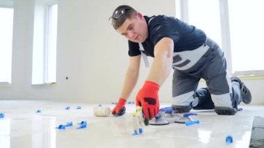 Endüstriyel tiler Profesyonel İnşaatçı döşeme tadilatı için seramik bir fayans yerleştiriyor. Ev ya da apartmanın içine fayans döşeyen adam tecrübeli bir tamirci. Bitirme çalışmaları