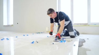 Endüstriyel tiler Profesyonel İnşaatçı döşeme tadilatı için seramik bir fayans yerleştiriyor. Ev ya da apartmanın içine fayans döşeyen adam tecrübeli bir tamirci. Bitirme çalışmaları