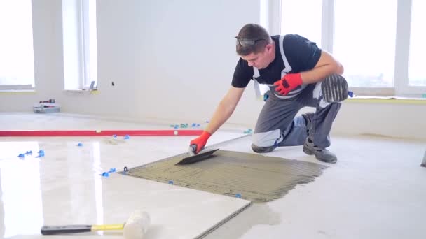 用工具和胶水搅拌器对混凝土地板上的瓷砖进行施工维修 工人修理工人工造型师 凹槽式排便贴面与凹槽式排便粘合剂 — 图库视频影像