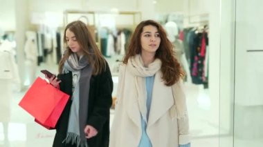 Paltolu iki genç kadın AVM 'de dolaşıp akıllı telefonlarda indirimlere ve satışlara bakıyorlar. Hediye çantalı iki kız ellerinde telefonla giyim mağazasına giriyorlar. Kara Cuma