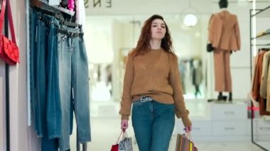 Alışveriş merkezindeki giyim mağazasında hediye olarak alışveriş torbalarıyla dolaşan çekici bir kadının portresi. Kara Cuma 'da indirimde olan genç ve güzel bir alışveriş kızı.