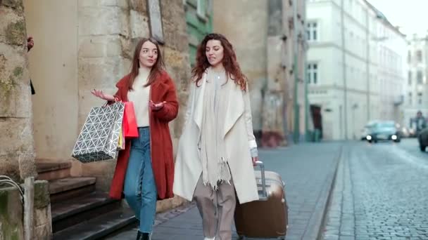 Zwei Junge Touristinnen Gehen Mit Einem Koffer Und Geschenktüten Durch — Stockvideo