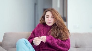 Kanepede burnu akan hasta bir kız portresi. Soğuk algınlığı ya da soğuk algınlığı belirtileri gösteren sıcak örgü süveter giyen genç bir kadın peçetelerle burnunu siler. Kanepede oturan kadın.