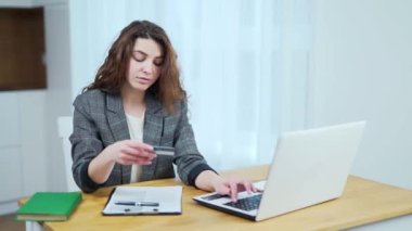 Beyaz kadın portresi evde masada oturuyor. Kredi kartıyla online ödeme yapıyor. İnternetten alışveriş yapan mutlu genç kadın. 