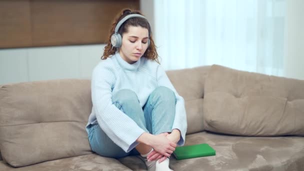 Portrait Sad Pensive Young Woman Listening Music Headphones Sitting Sofa — Stock Video