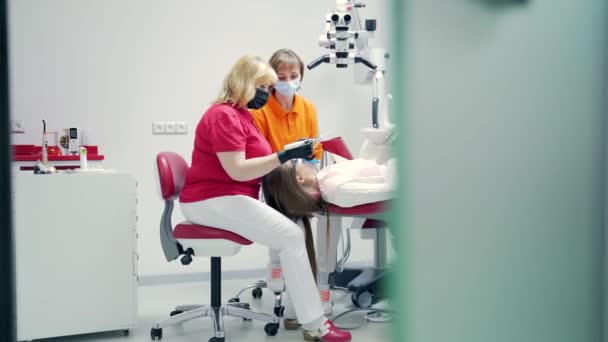 资深的有经验的女牙医在牙科诊所用现代化的设备填满了运河 关闭通道 用一种特殊的光聚合物物质处理工具牙的新方法 — 图库视频影像